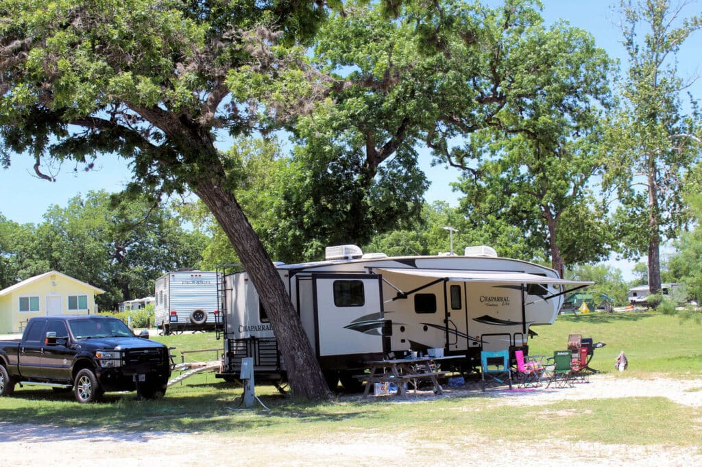 An RV parked near some trees in the shade at Camp Riverview