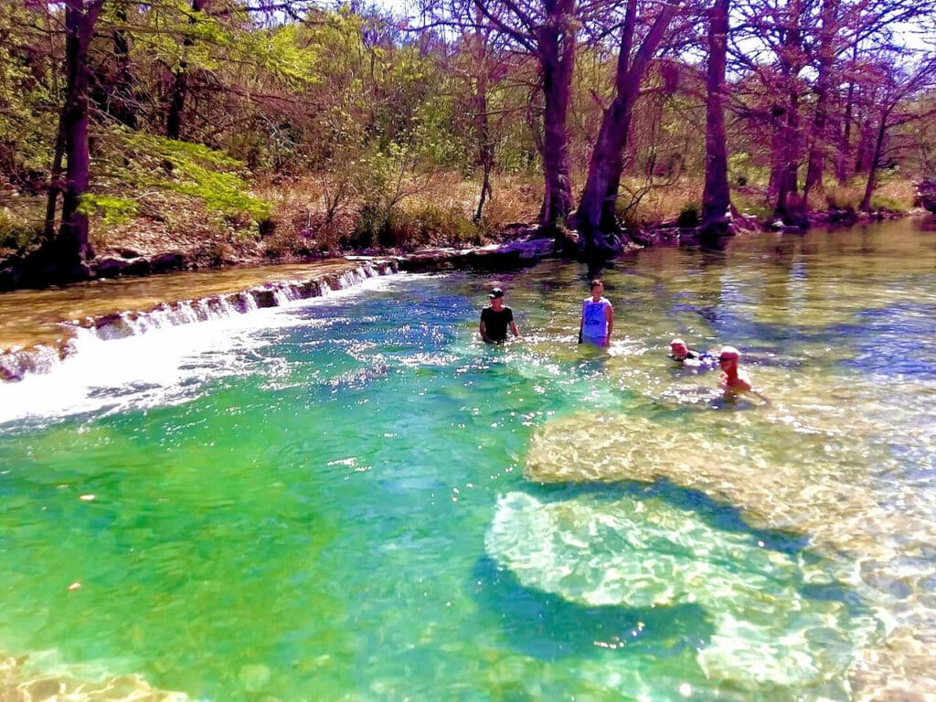 A family playing in the Frio River next to Camp Riverview.