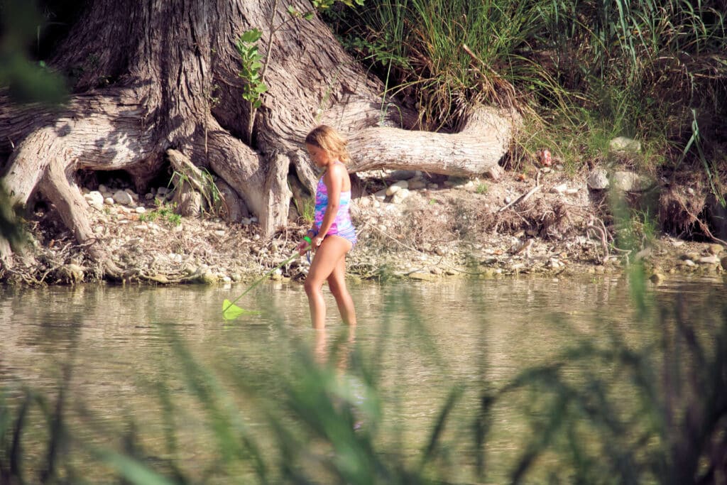 Little girl walking in the shallows of the Frio River at Camp Riverview