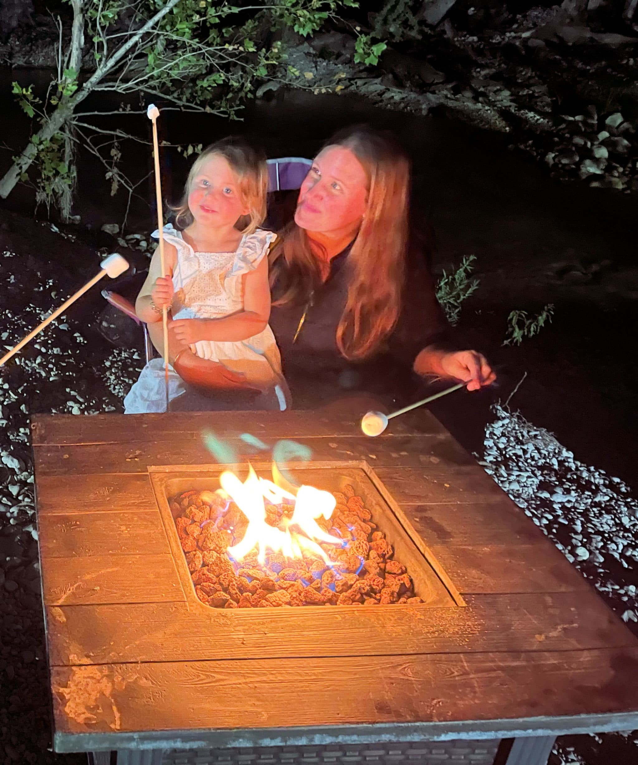 Mom and daughter roasting marshmallows at a campfire