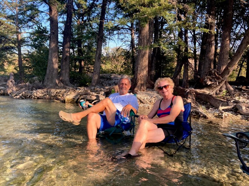 a couple sitting in folded chairs in the banks of the Frio River